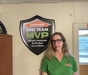 Female standing in front of tan wall next to sign reading Servpro One Team